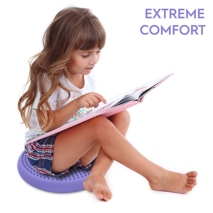 Child sitting on a round, purple sensory cushion with a textured surface while reading a book.
