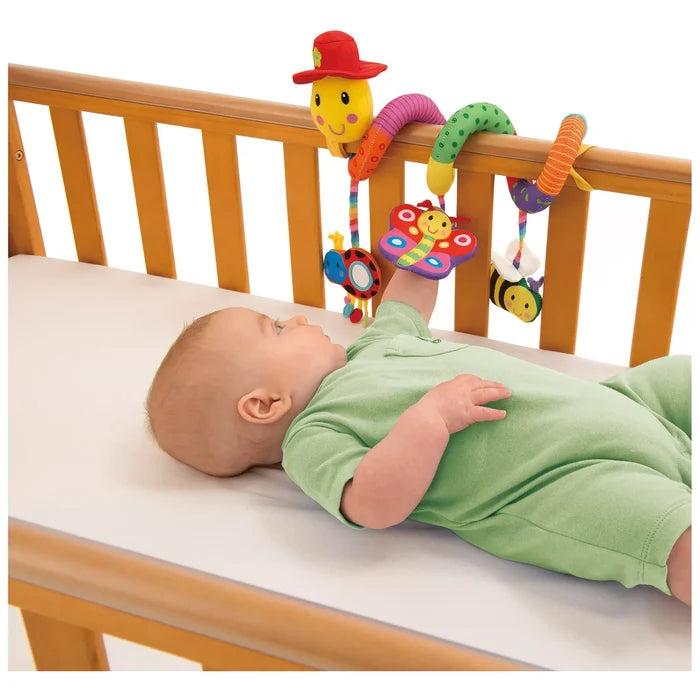 Colorful spiral worm toy with hanging bee, ladybug, and butterfly attached to a wooden crib rail.