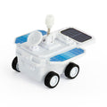 White toy space rover with black wheels, blue solar panel stickers, a satellite dish, and a white wind-up knob on top.