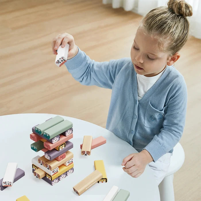 Child stacking colorful rectangular wooden blocks with cute animal faces on a white table.