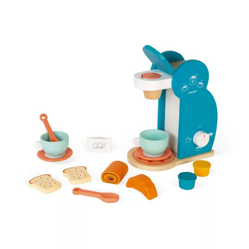 Teal wooden toy coffee machine with blue cups, orange saucers, spoons, toast, croissant, and coffee pods.