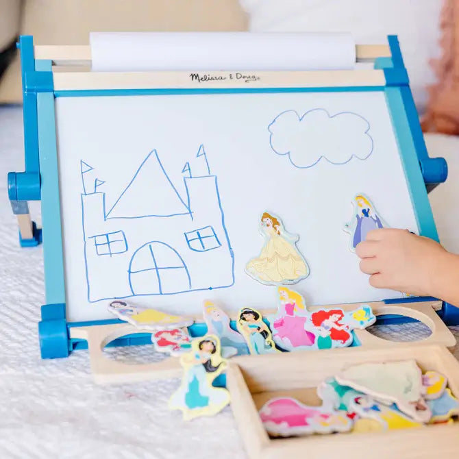 Blue wooden tabletop easel with a whiteboard, castle drawing, and several Disney Princess magnets.