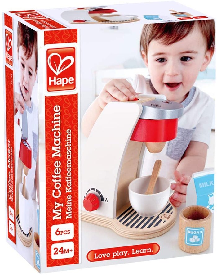 Hape wooden toy coffee machine packaging featuring a white and red machine, cup, spoon, and a toddler playing.