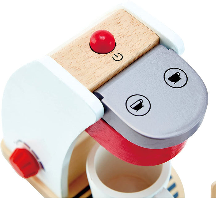 White wooden toy coffee machine with a red button, silver lid with cup icons, and a white toy mug.