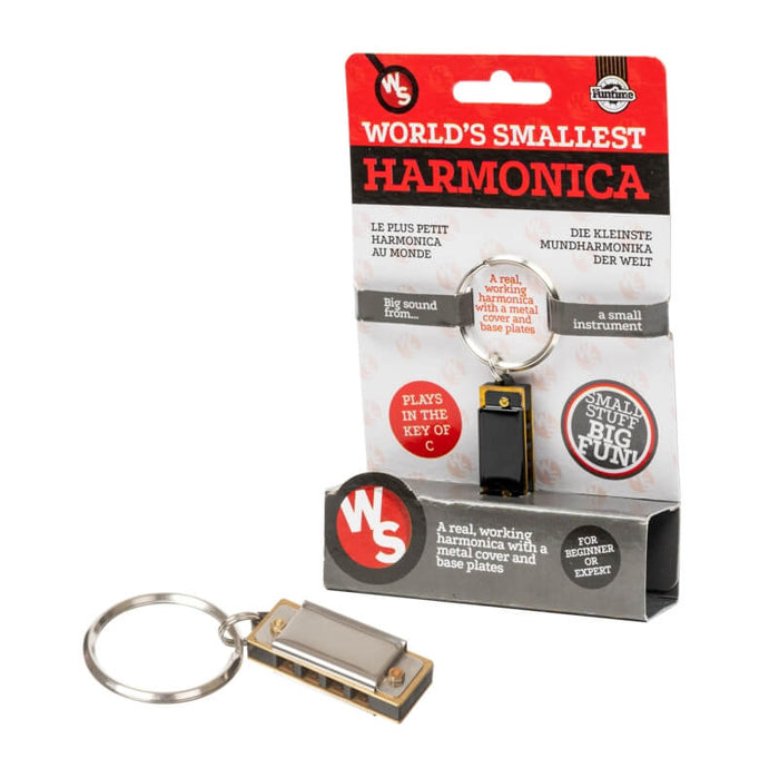 Tiny silver and brass harmonica on a keychain ring next to its red and white retail display packaging.