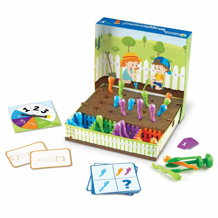 Toy garden game with colorful plastic worms in holes, a green grabber tool, activity cards, and a numbered spinner.