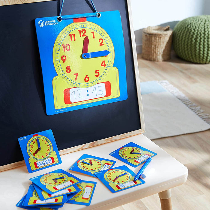 Large blue and yellow demonstration clock on a blackboard with matching small wipe-off clock cards and a marker.